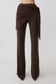 Woman wearing brown straight leg pants with waist wrap.
