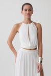 Woman wearing a white halter neck top with hardware.