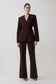 Woman wearing a dark brown drop shoulder suiting blazer with matching flare suiting pants.