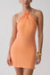 Woman wearing a orange cupro halter mini dress.