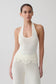 Woman wearing white crochet halter longline top.