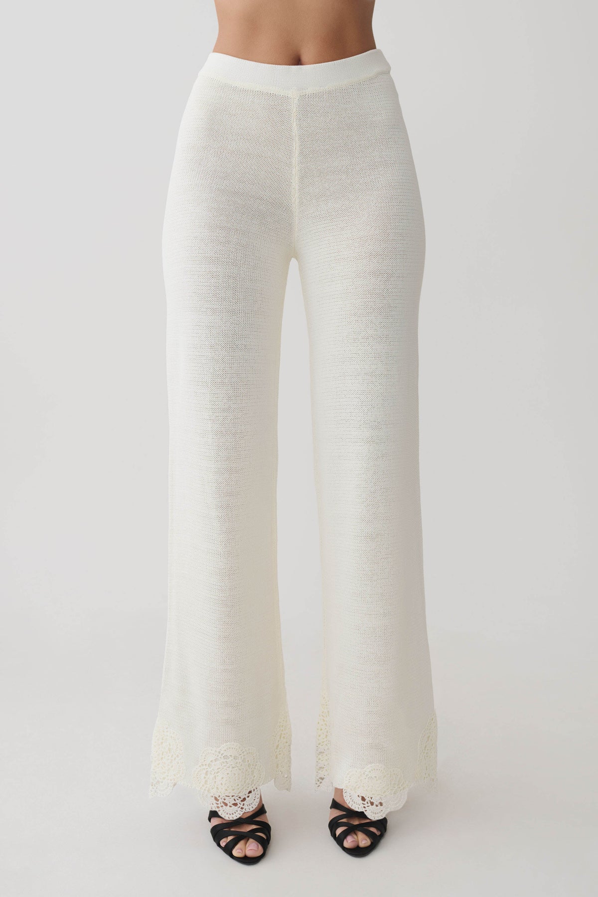 Woman wearing white crochet pants.