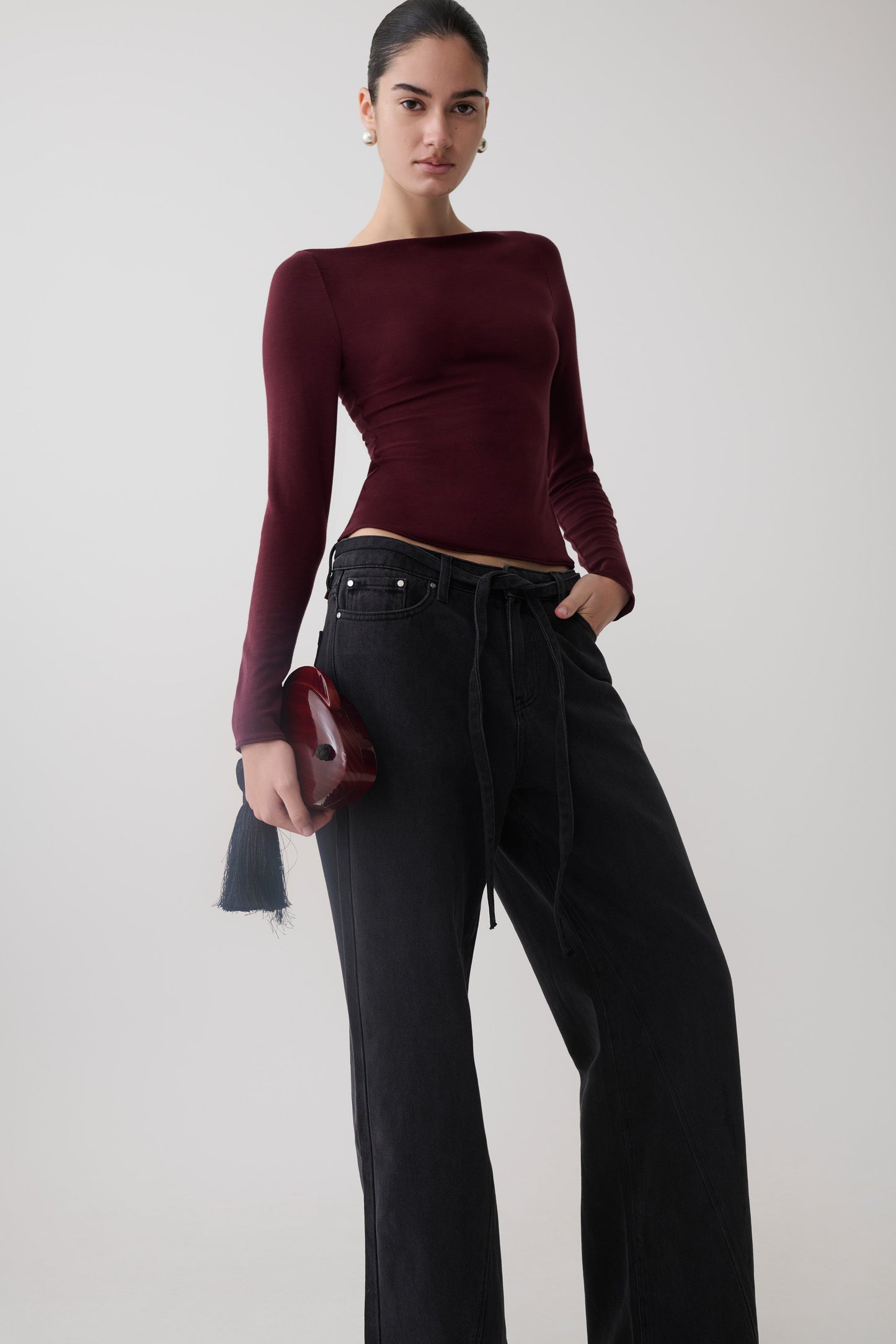 Woman wearing a burgundy long sleeve sheer top.