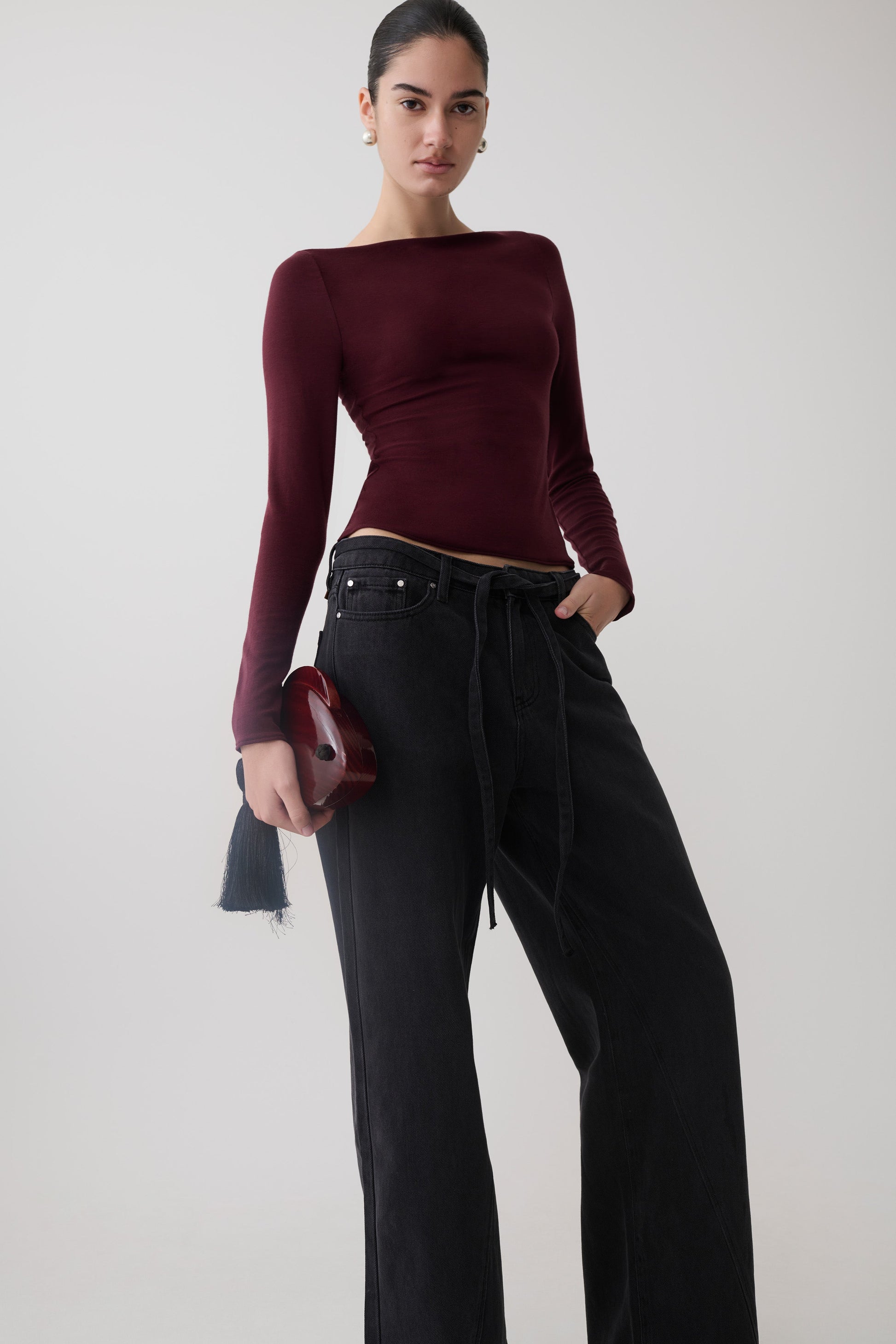Woman wearing a burgundy long sleeve sheer top.