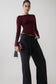 Woman wearing a burgundy long sleeve sheer top.