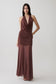 Woman wearing a brown draped halter slinky maxi dress.