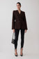 Woman wearing a brown blazer and knit black leggings.