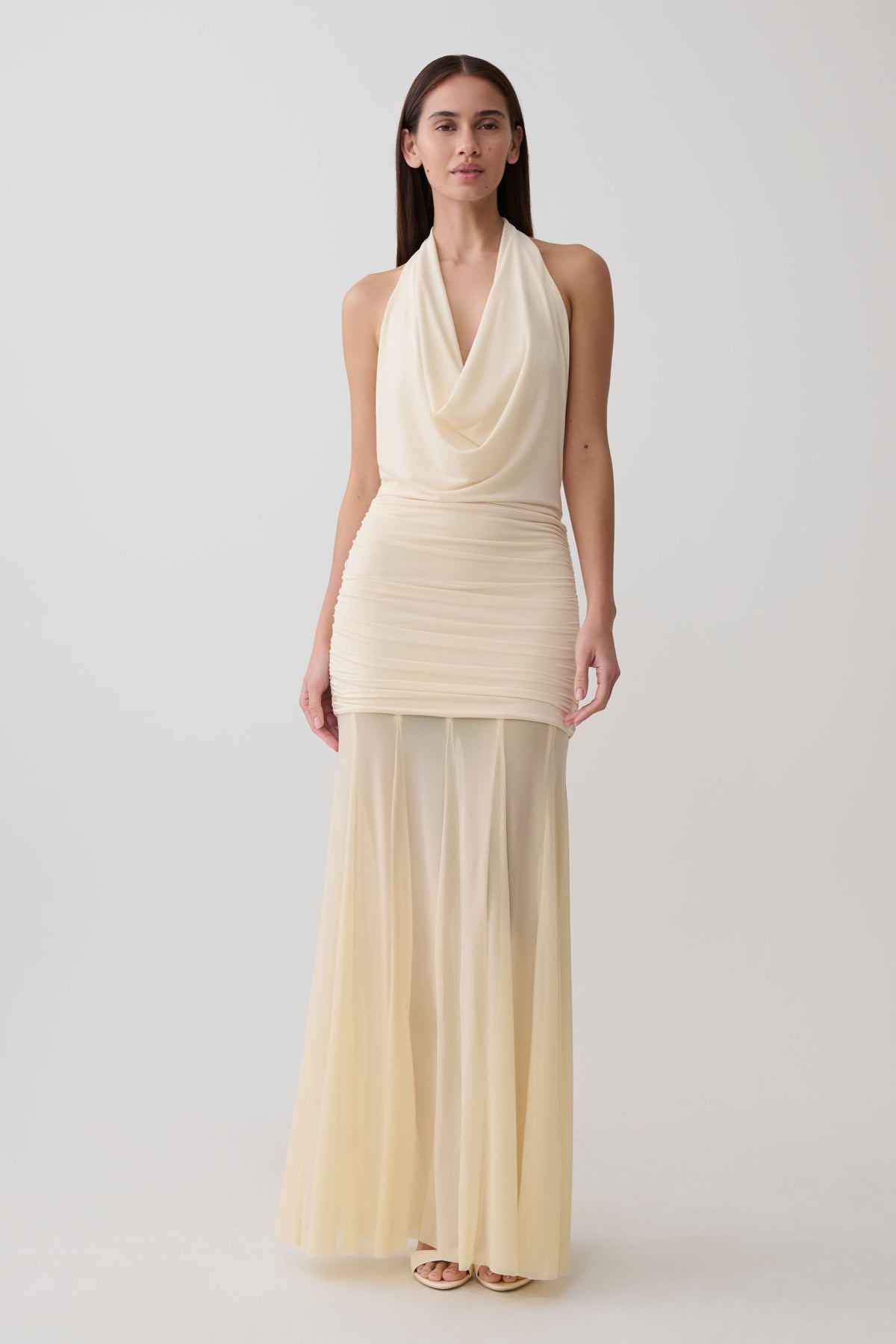 Woman wearing a white draped halter slinky maxi dress.