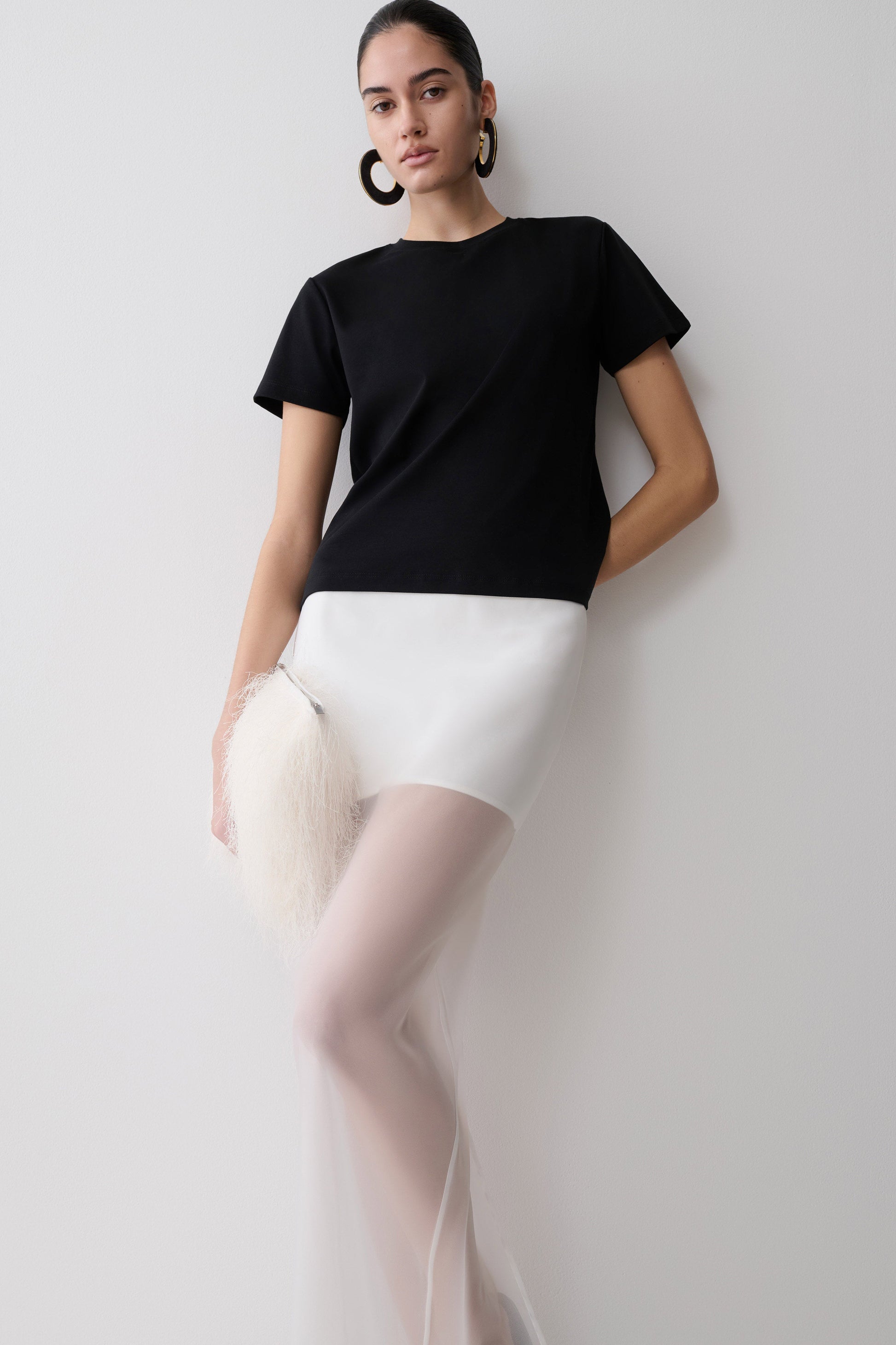 Woman wearing a black t-shirt and white organza maxi skirt.