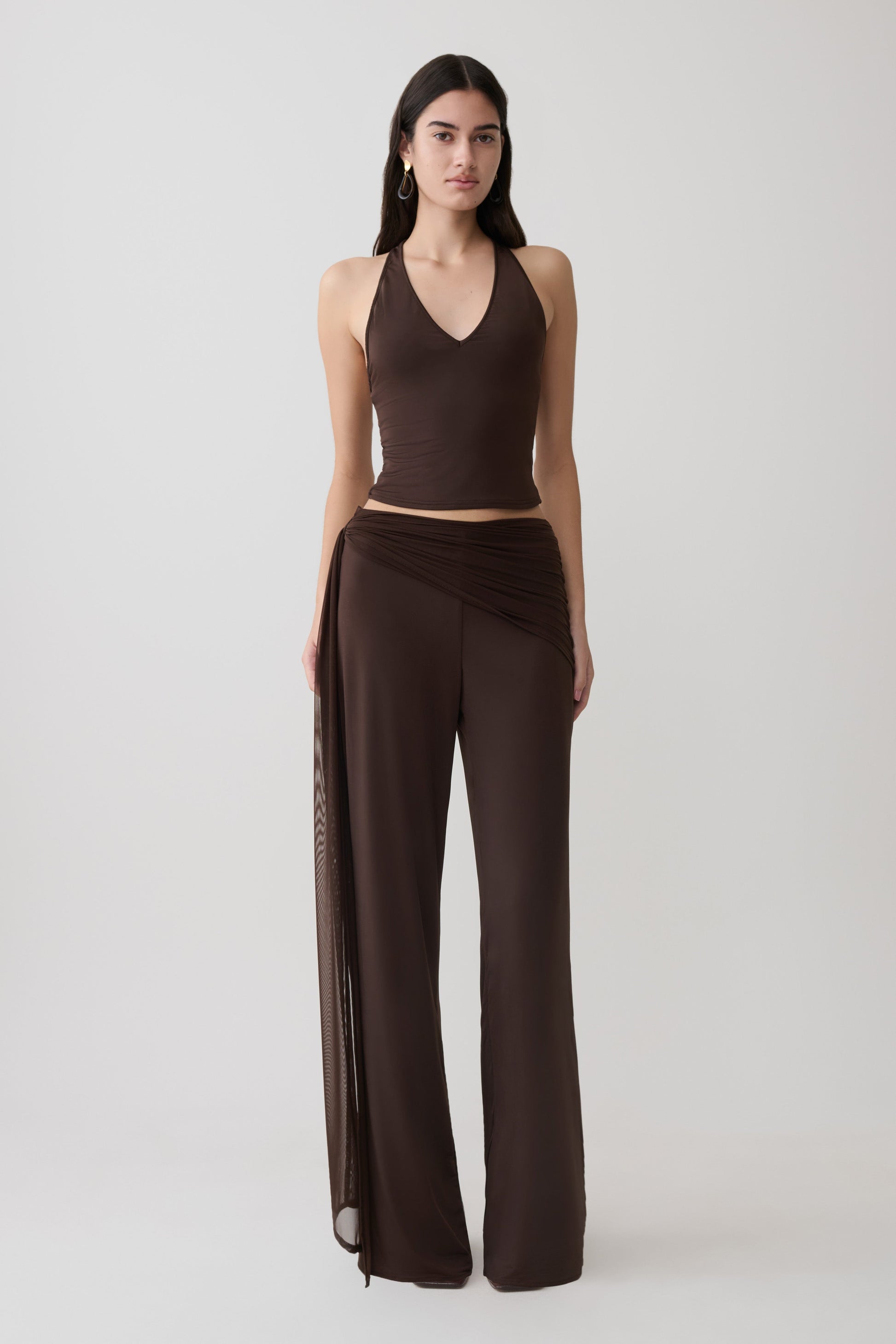 Woman wearing a brown slinky and mesh top with slinky gathered wide leg pants.