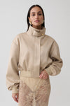 Woman wearing a gold satin bomber jacket.