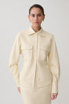 Woman wearing white faux leather shirt.