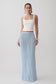 Woman wearing a white top and light blue crochet knit maxi skirt.