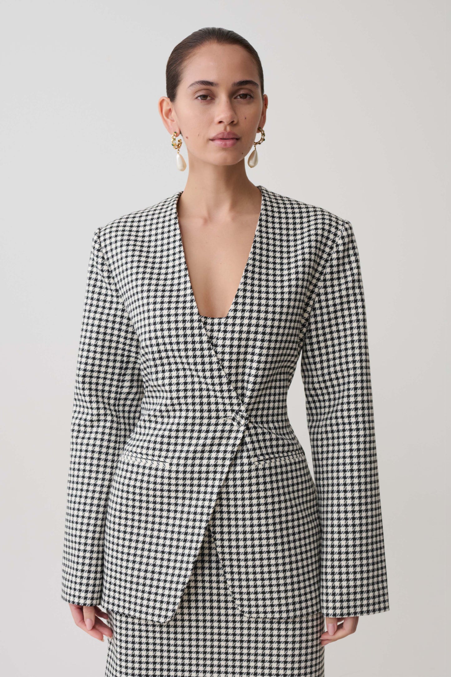 Woman wearing a black and white checkered drop shoulder suiting blazer.