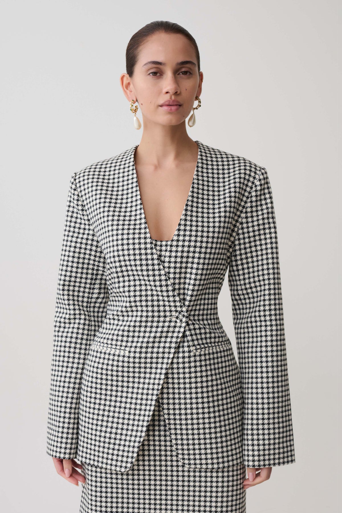 Woman wearing a black and white checkered drop shoulder suiting blazer.