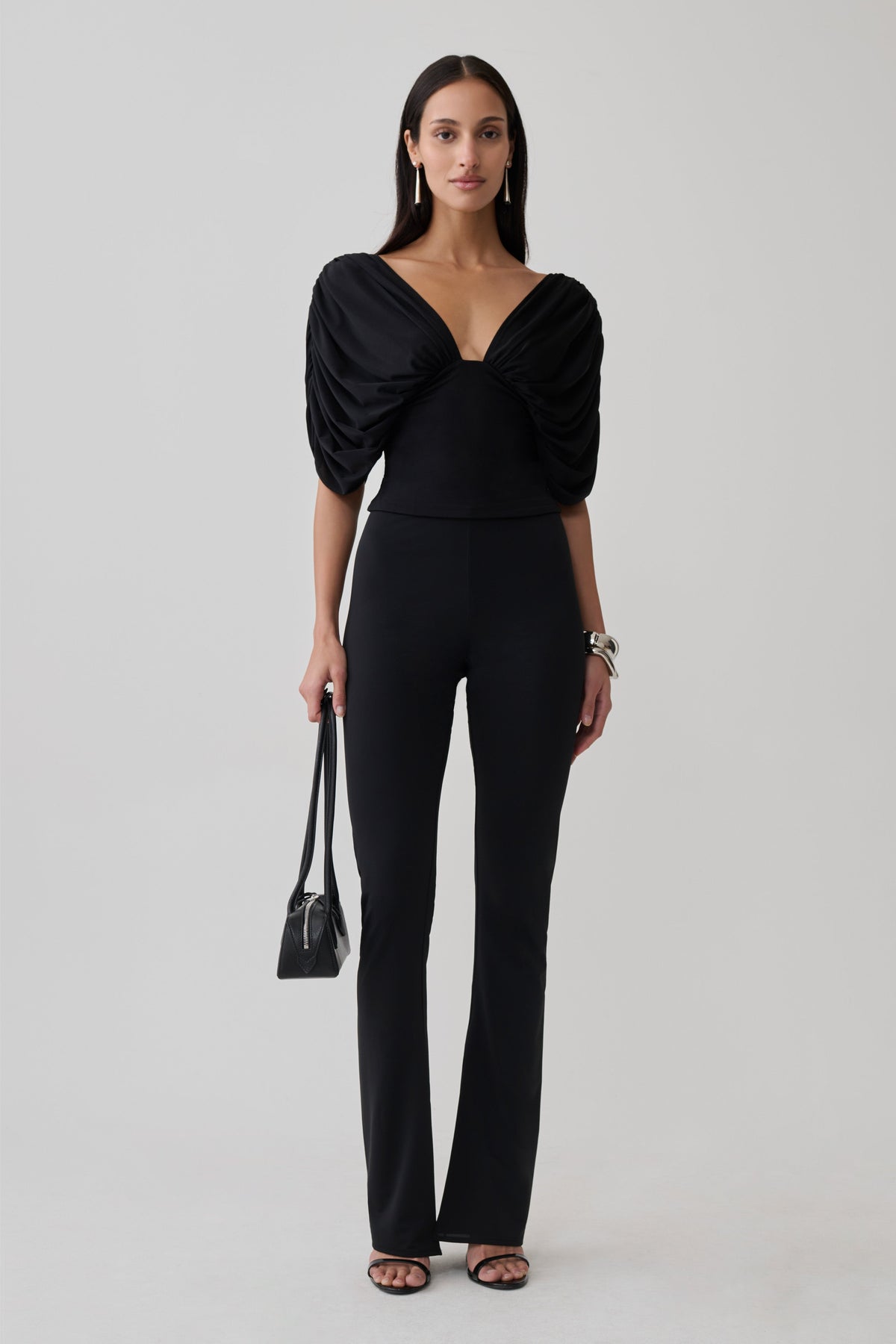Woman wearing a gathered bodice top with skinny flare pants.