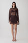 Woman wearing brown bralette with chiffon cape with matching lace and satin mini skirt.