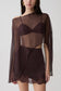 Woman wearing brown bralette with chiffon cape with matching lace and satin mini skirt.
