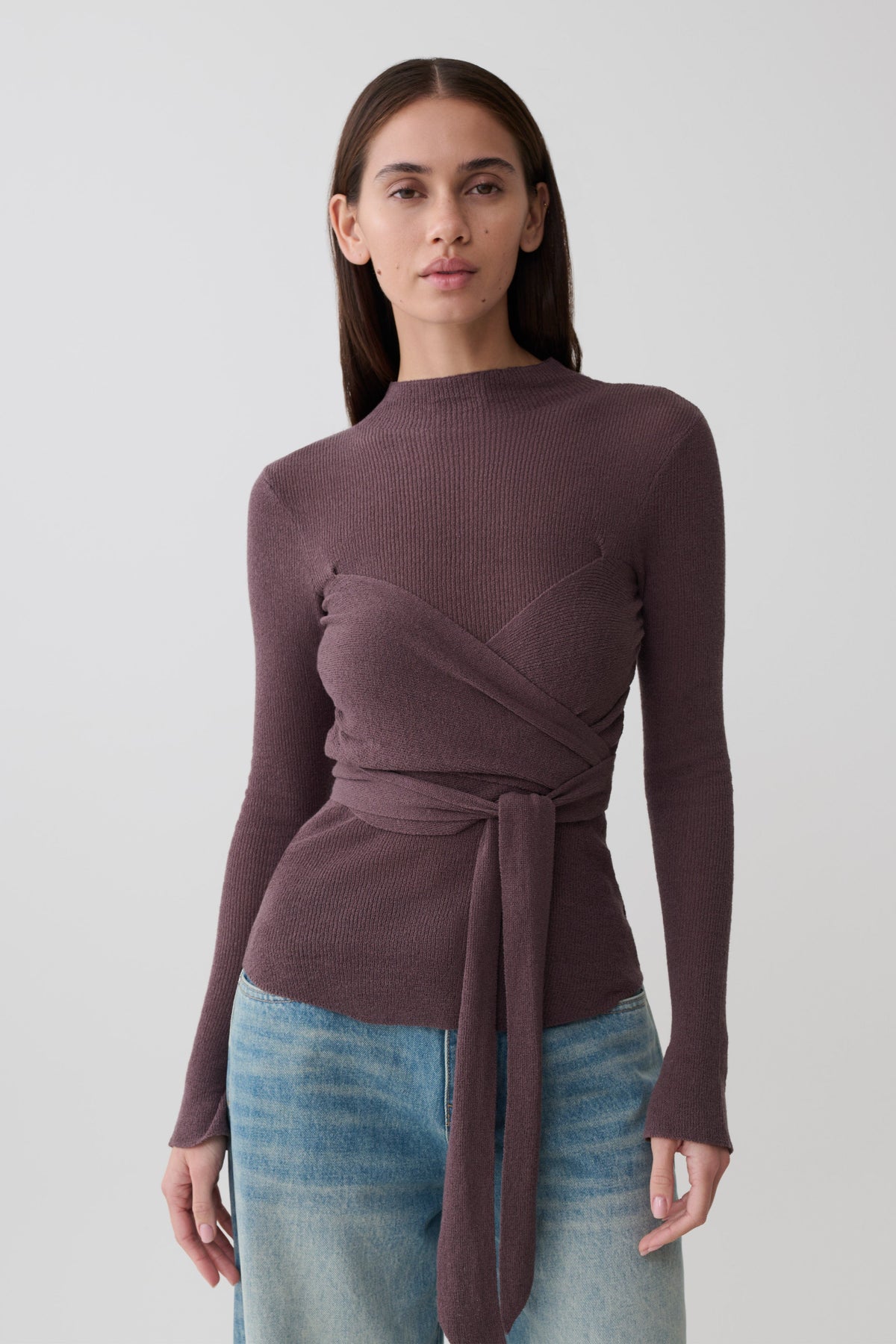 Woman wearing a brown wrap knit long sleeve top.