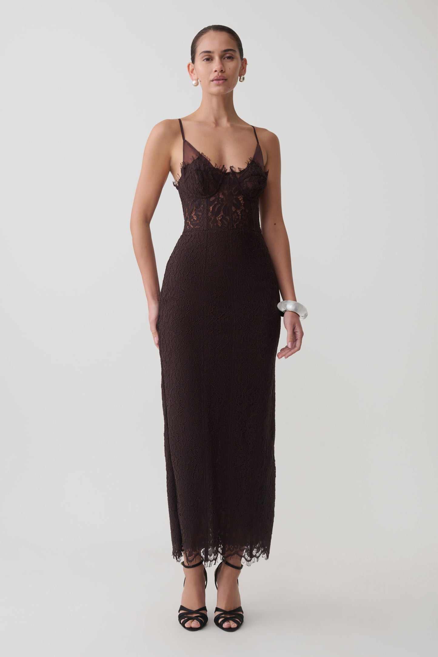 Woman wearing a dark brown lace and mesh midi dress.