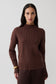 Woman wearing a brown ribbed high neck jumper.