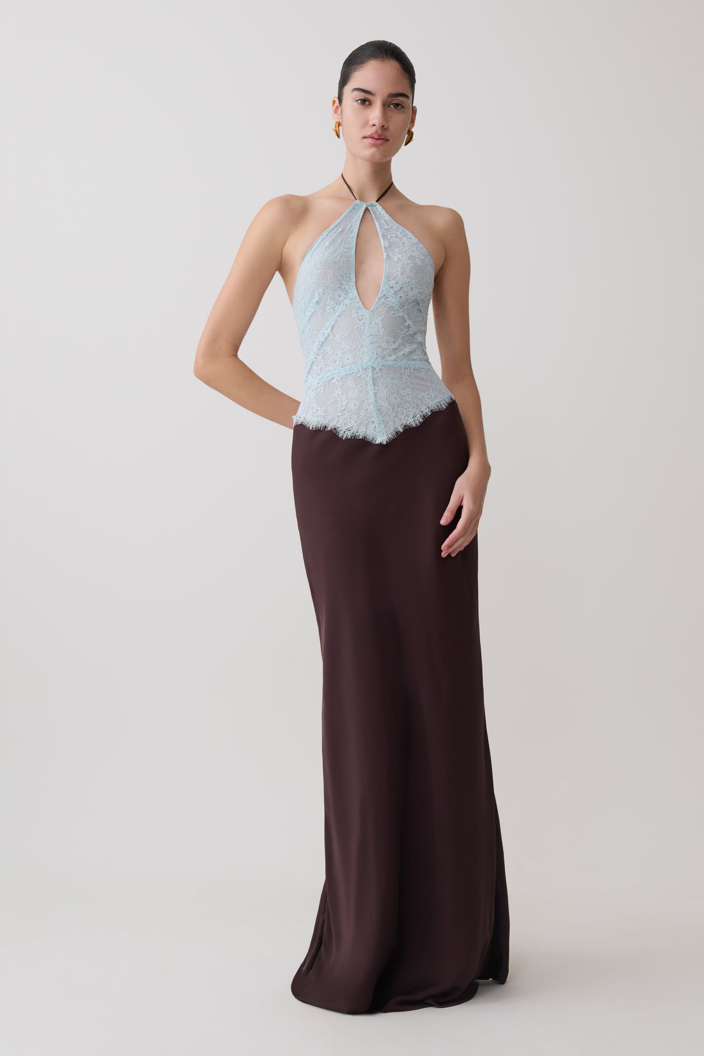 Woman wearing a light blue and dark brown lace and satin halter maxi dress.