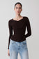 Woman wearing a brown long-sleeve draped twist knit top.