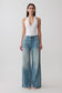 Woman wearing a white slinky halter bodysuit paired with jeans.