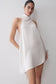 Woman wearing a white asymmetrical satin halter mini dress.
