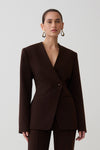 Woman wearing dark brown drop shoulder suiting blazer.