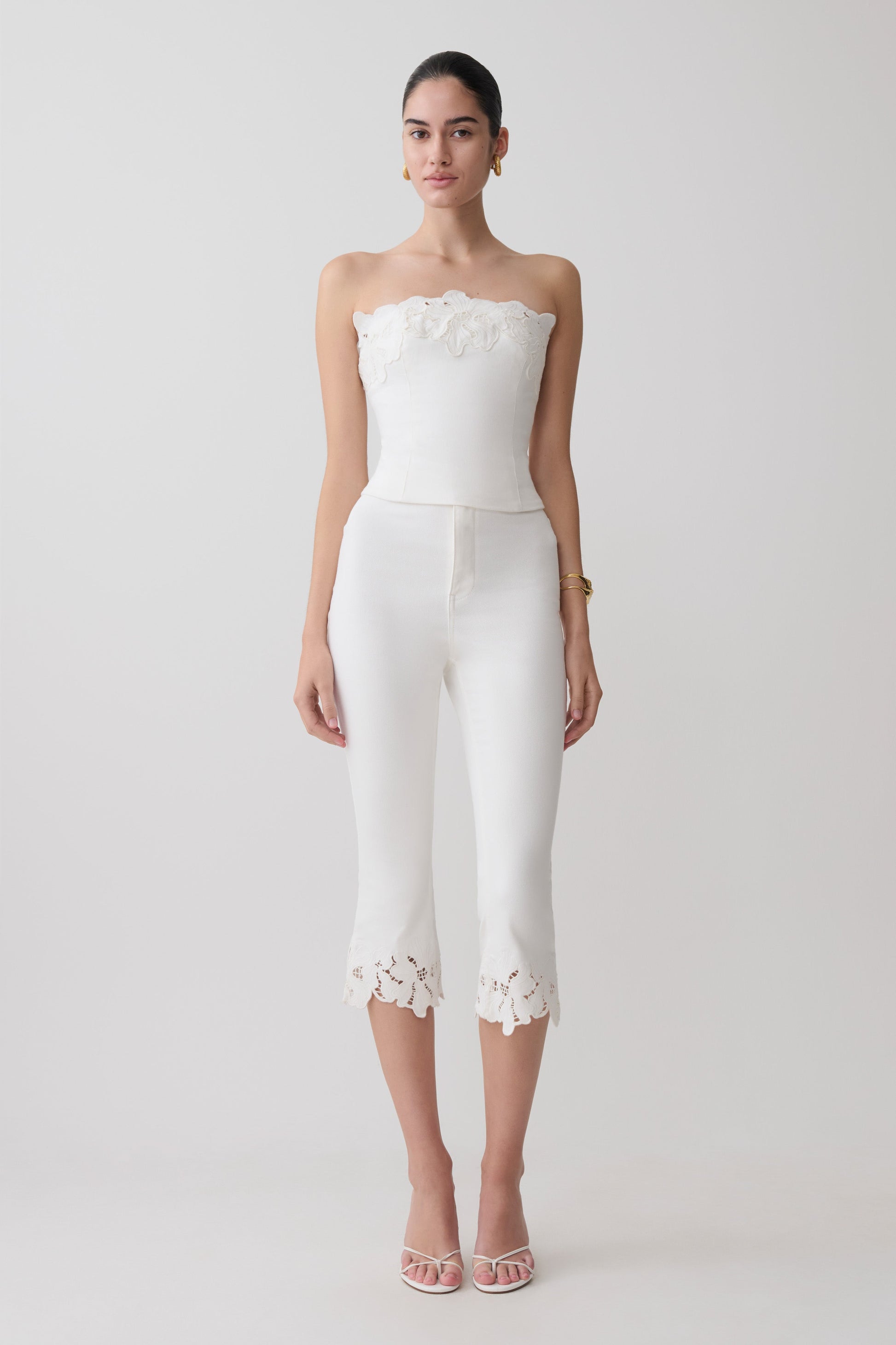 Woman wearing a white embroidery strapless denim top and white flower embroidery denim capris.