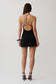 Woman wearing a black mini dress with silver hardware.