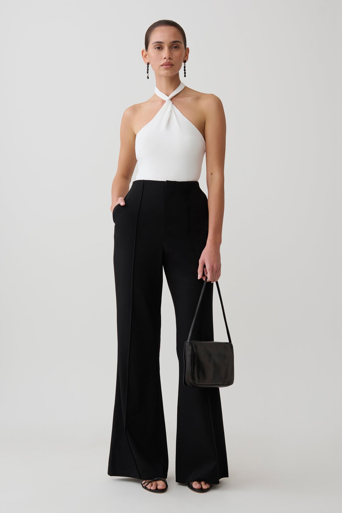 Woman wearing a white twisted neck bodysuit.