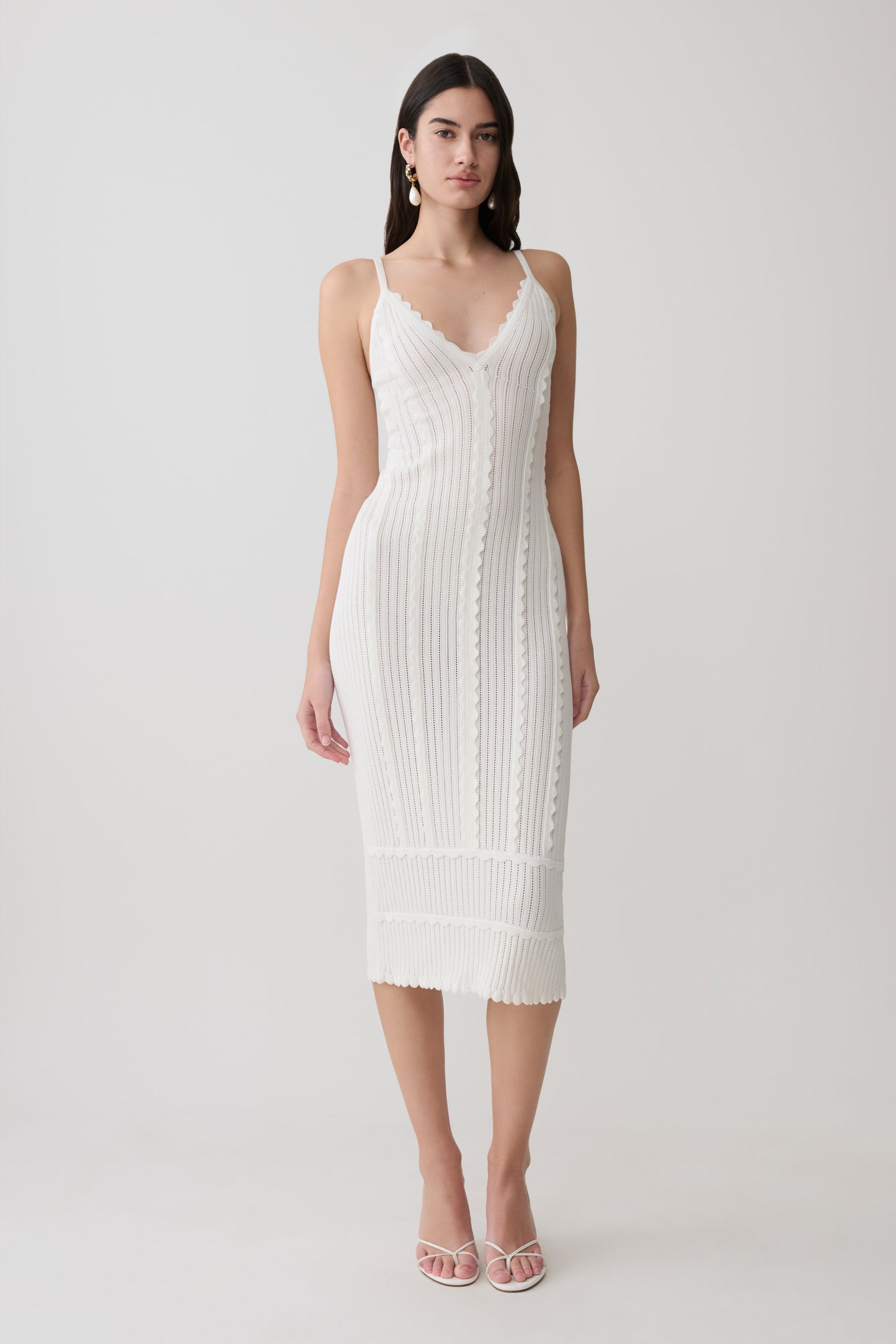 Woman wearing a white scalloped neckline pointelle midi dress.