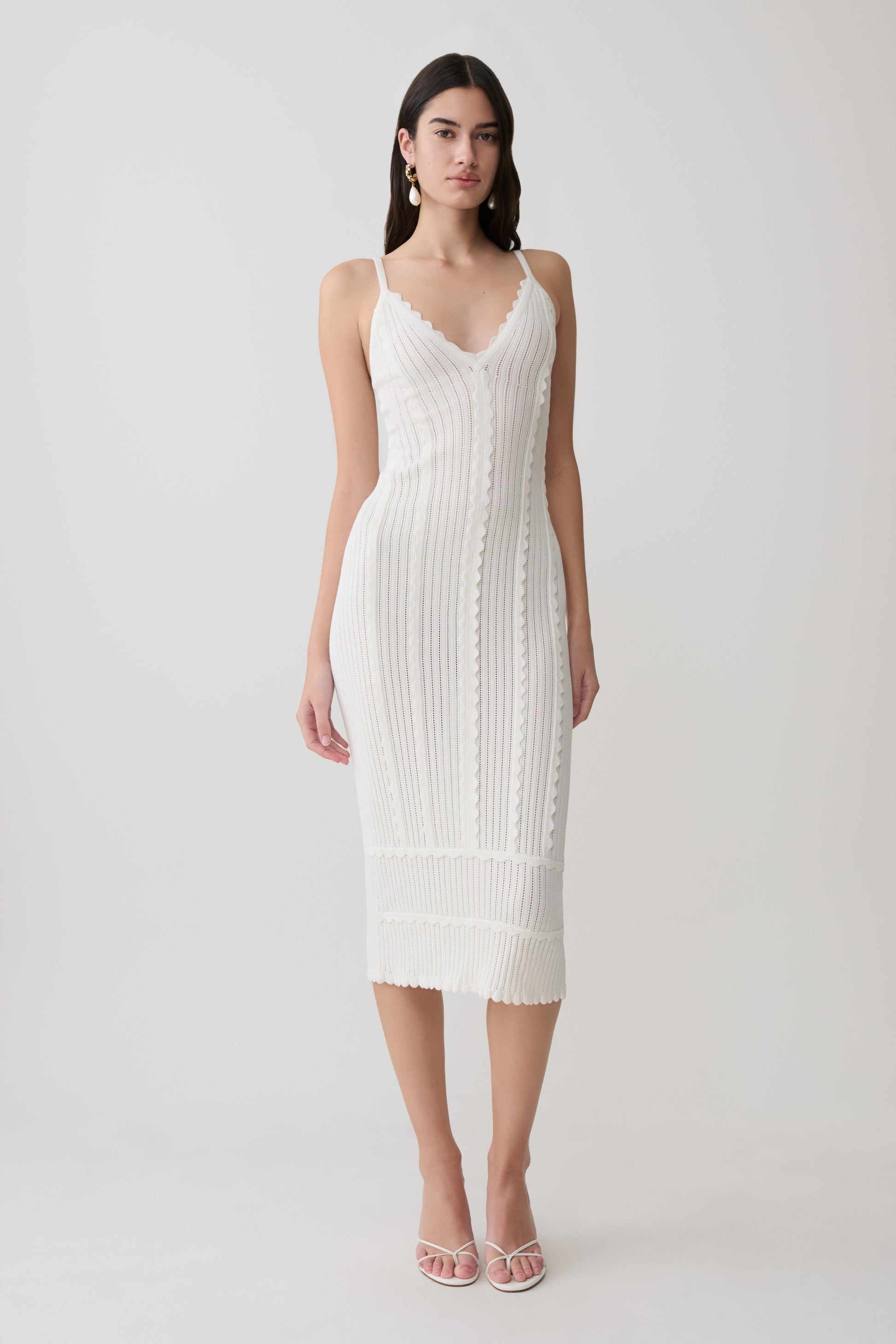 Woman wearing a white scalloped neckline pointelle midi dress.