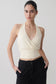 Woman wearing a white draped halter top.