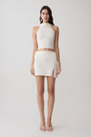 Woman wearing a white halter backless knit top with matching skirt.