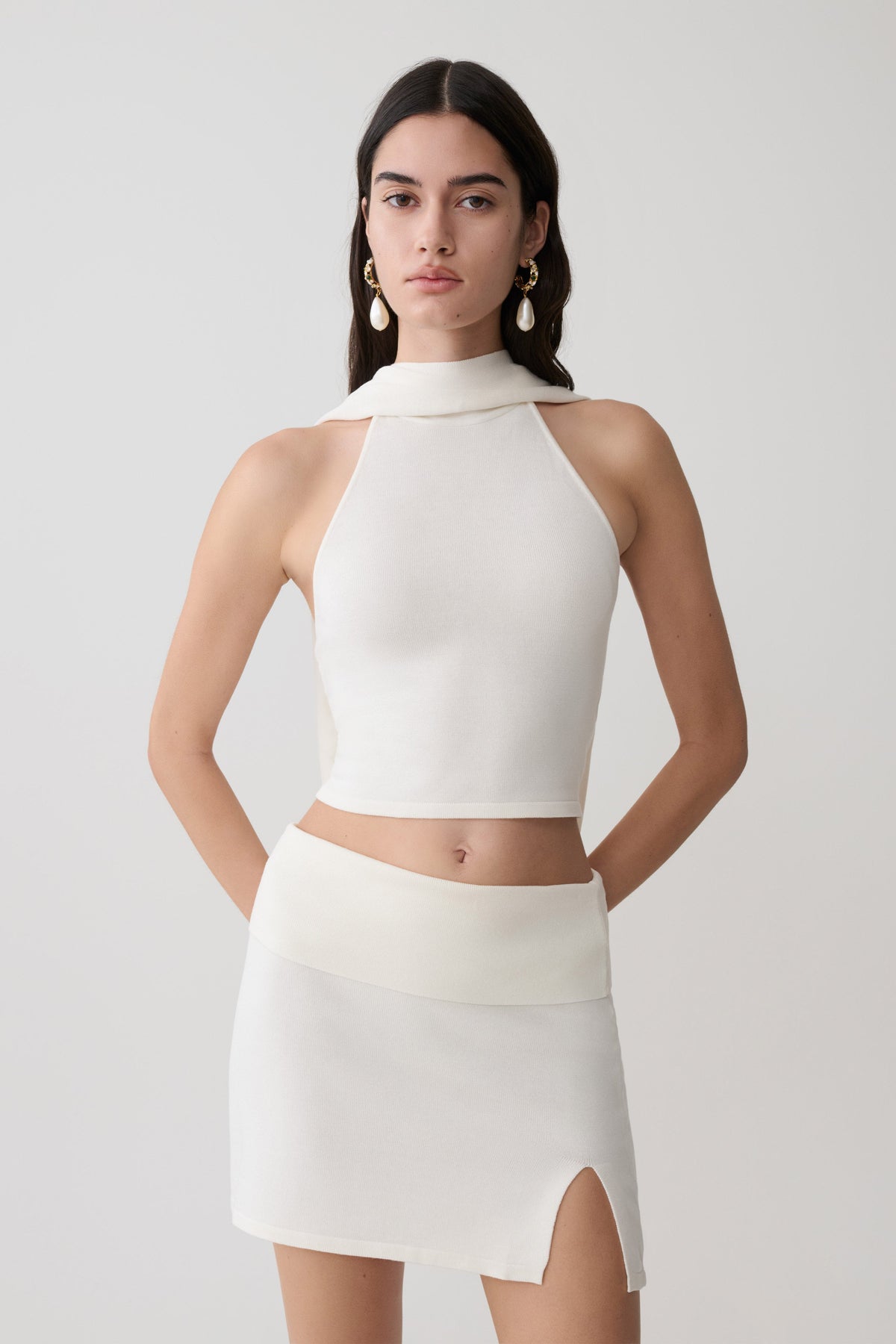 Woman wearing a white halter backless knit top with matching skirt.