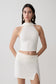 Woman wearing a white halter backless knit top with matching skirt.