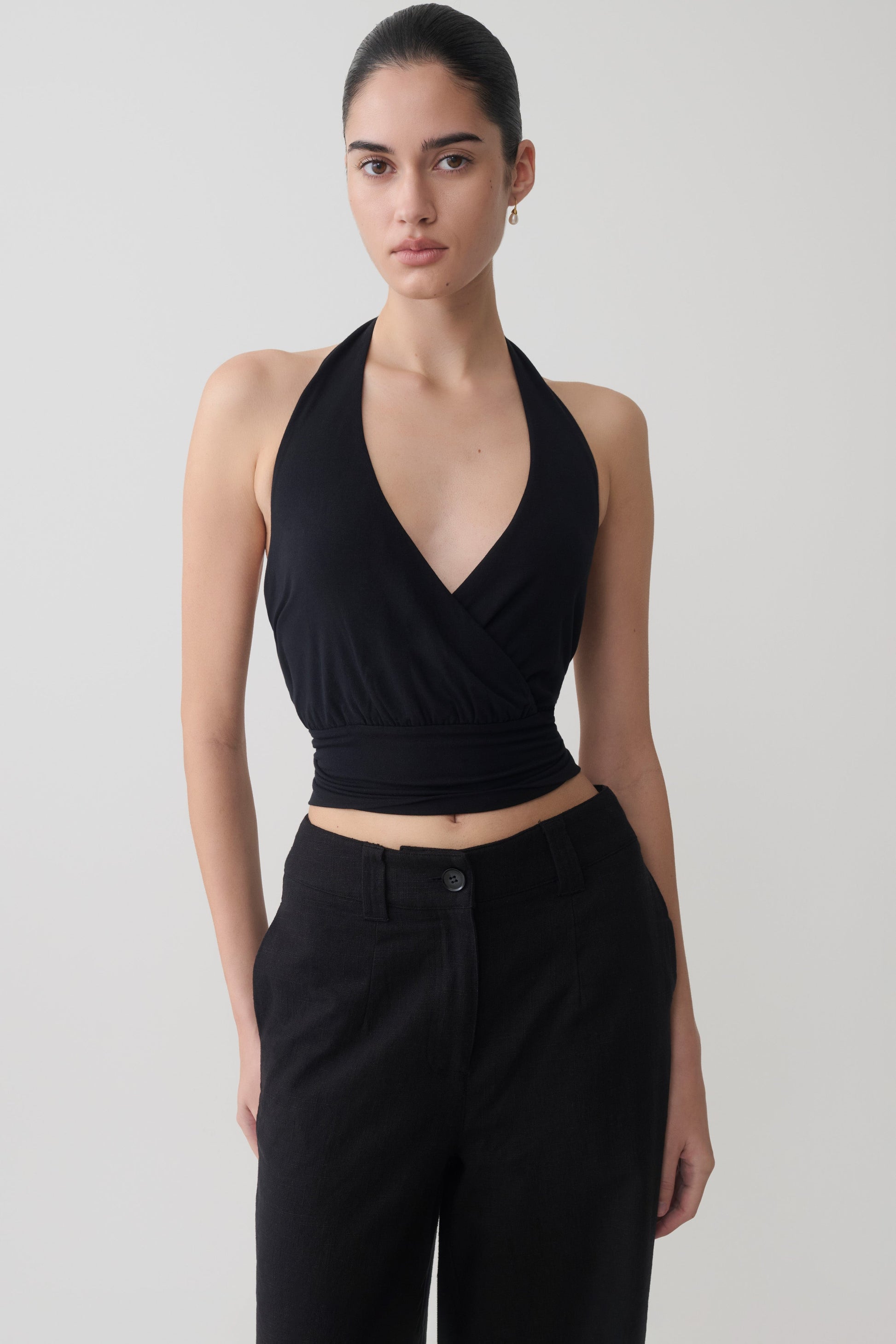 Woman wearing a black draped halter top. 