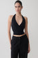 Woman wearing a black draped halter top. 