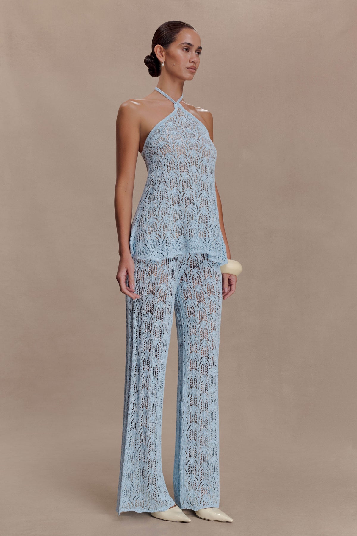 Woman wearing a light blue crochet halter top.
