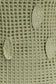 Close-up of a textured green crochet fabric with leaf detailing.