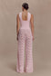 Woman wearing a pink knit top and crochet pants.
