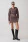 Woman wearing a brown knitted outfit with black knee-high boots on a white background.