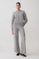 Person wearing a gray sweater and pants on a white background.