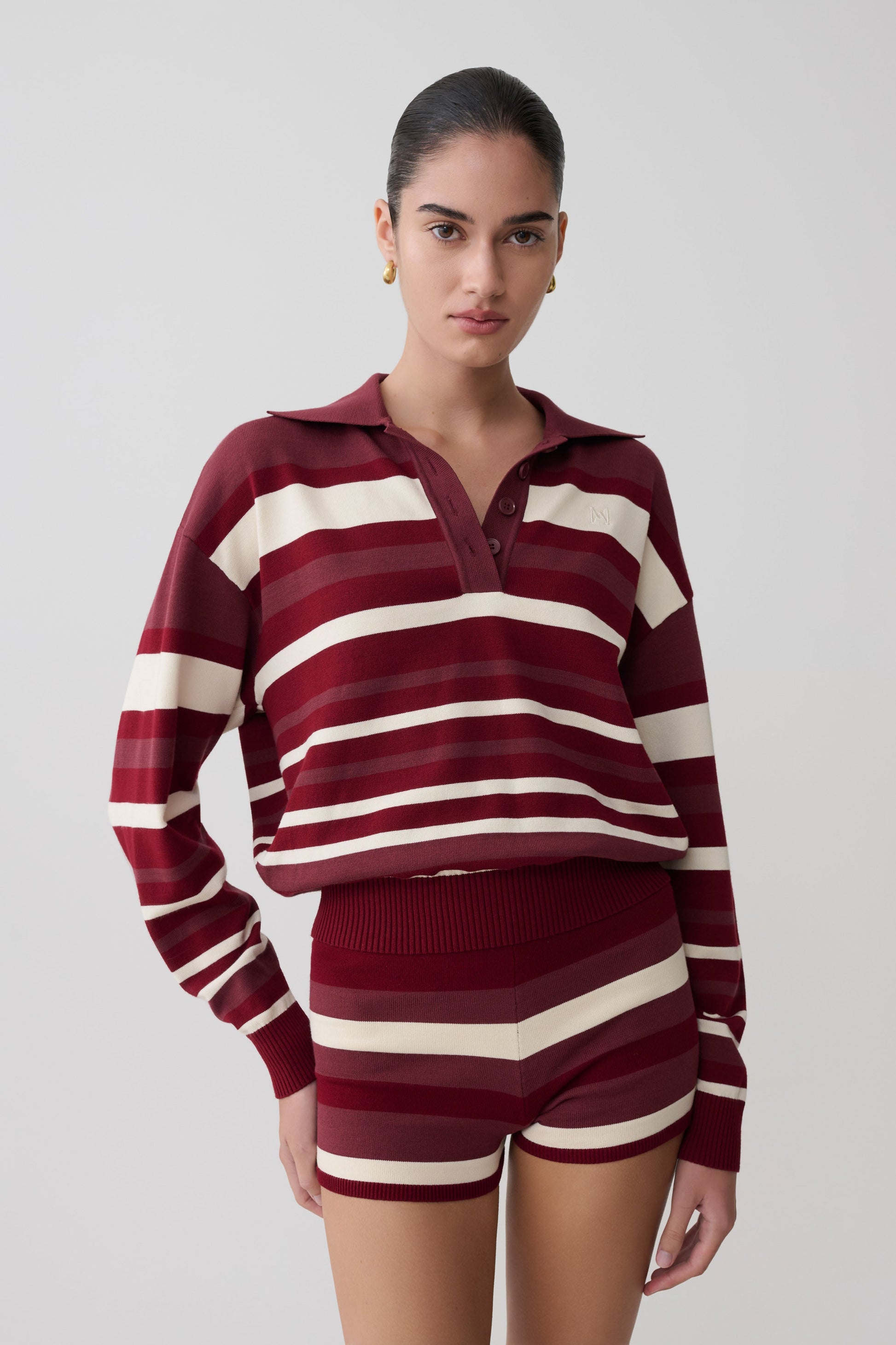 Woman wearing a maroon and white striped outfit on a plain background.