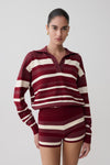 Woman wearing a maroon and white striped outfit on a plain background.