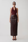 Woman wearing a burgundy halter top and dark brown leather skirt on a white background.