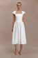 Woman wearing a white dress against a beige background